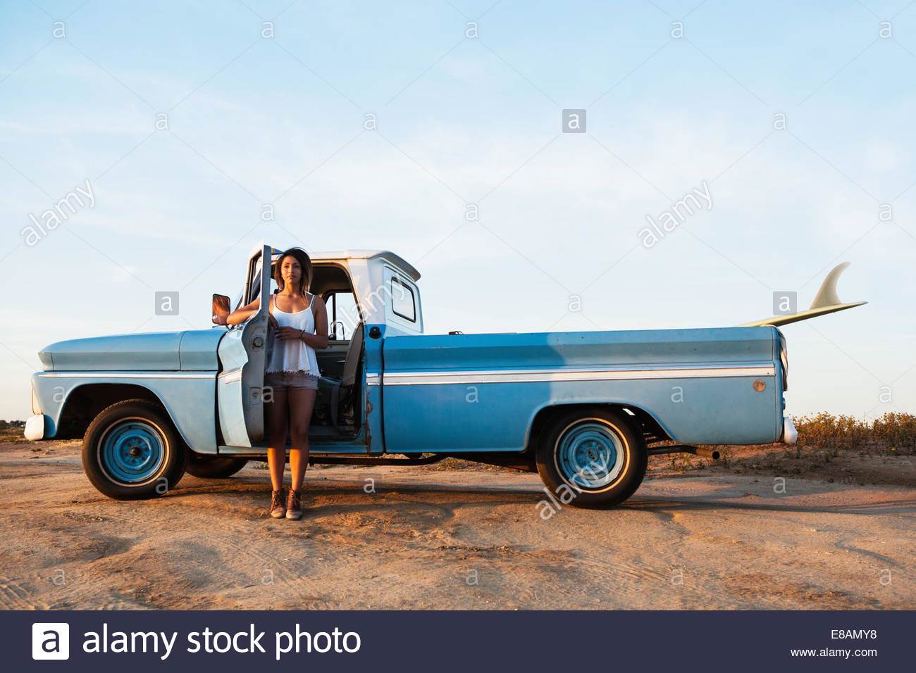 portrait-of-young-female-surfer-leaning-on-pick-up-truck-door-leucadia-E8AMY8